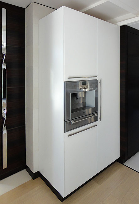 Meuble de cuisine sur mesure laqué blanc avec machine à café intégrée et poignées inox.